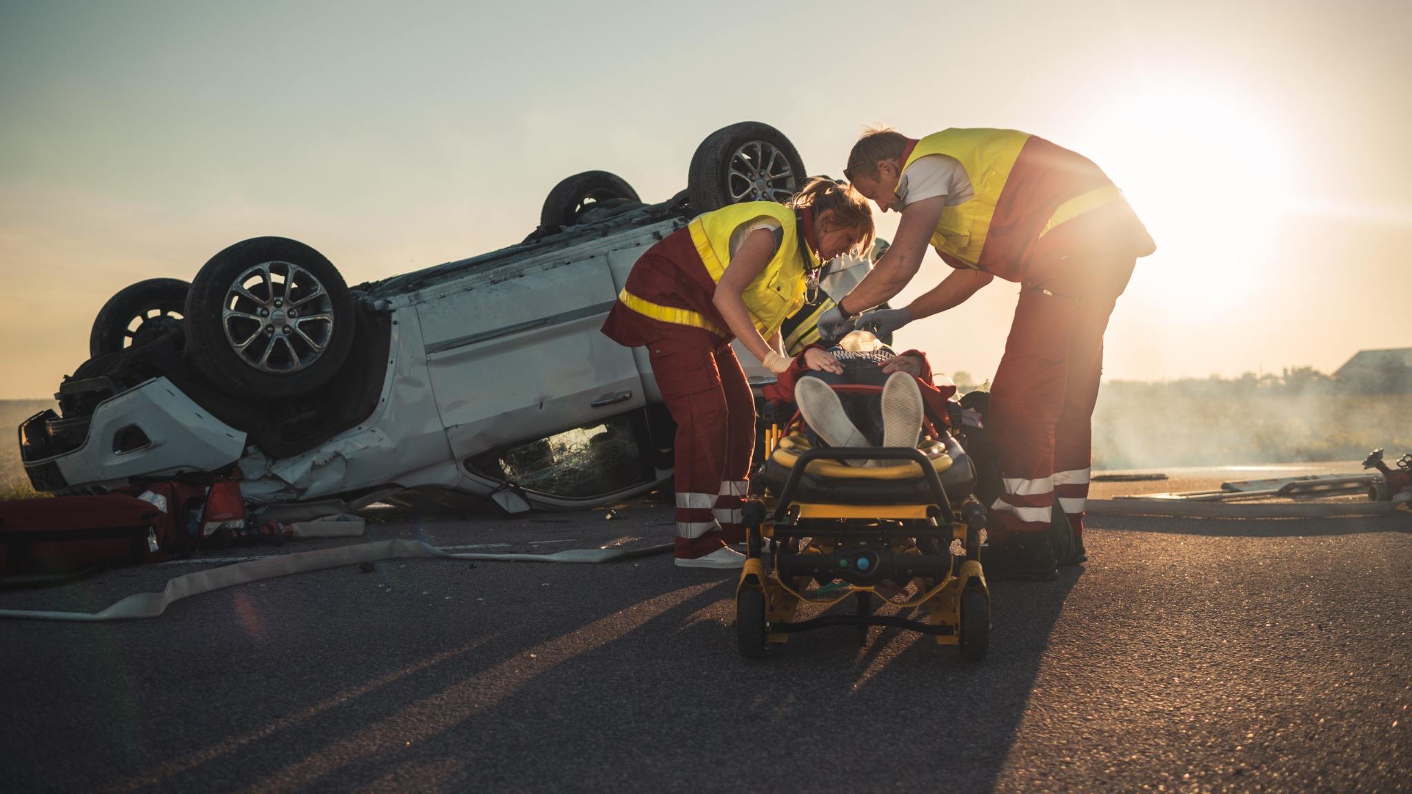 people pulling someone out of an overturned car